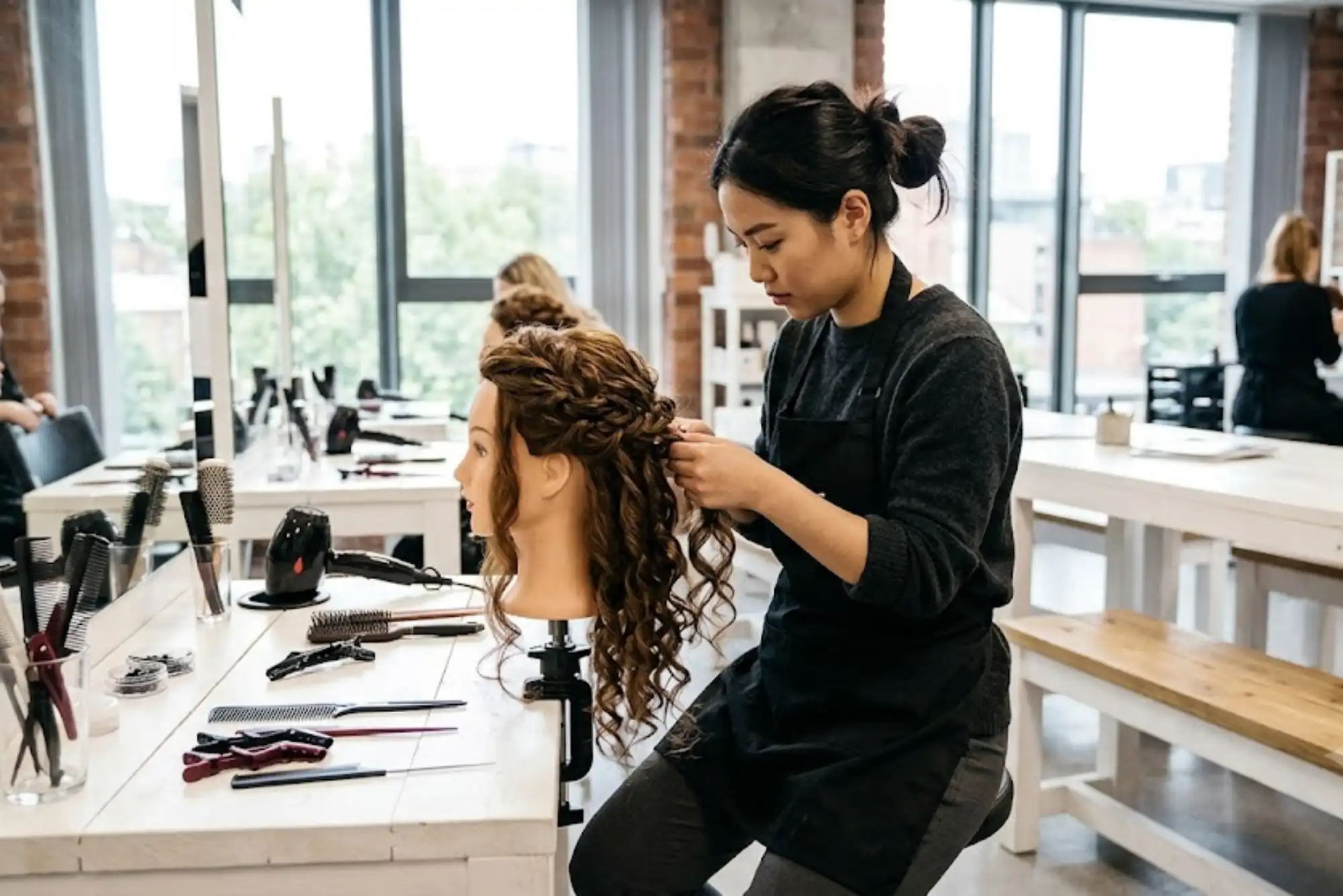 Beauty student practising hairstyling techniques on a mannequin head.
